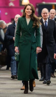 the duke and duchess of cambridge are walking together in green coats, black pants and brown shoes