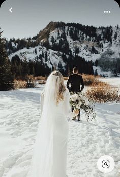 a bride and groom walking in the snow