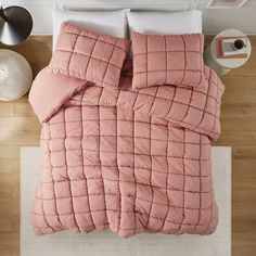 an overhead view of a bed with pink comforter and pillows