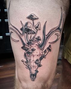 a man's leg with a deer skull and mushrooms on it