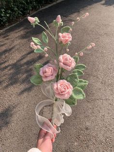 a person is holding a fake flower in their hand while walking down the street on a sunny day