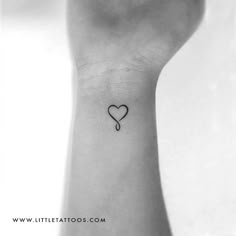 a small heart tattoo on the wrist with an arrow in the shape of a heart