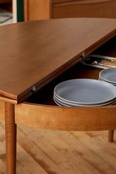 a wooden table with plates and silverware on it's bottom shelf, in the middle of a hardwood floored room