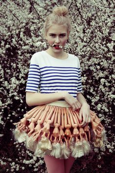 a woman standing in front of a bush wearing a skirt made out of fake bones