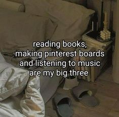 a pile of books sitting on top of a wooden floor next to a bed with white sheets