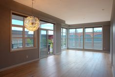 an empty room with wooden floors and large windows