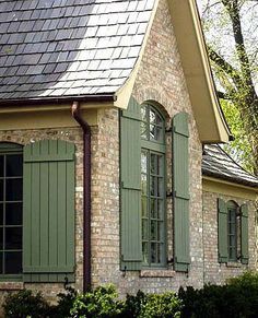 a brick house with green shutters and windows