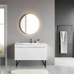 a white bathroom with a round mirror above the sink