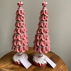 two pink christmas trees sitting on top of a wooden table