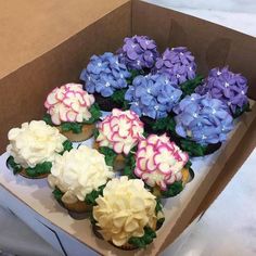 cupcakes decorated with flowers are in a box on the table and ready to be eaten