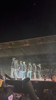 a group of people standing on top of a stage in front of a large crowd