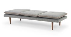 a gray bench with three pillows on it's back and two legs, sitting in front of a white background