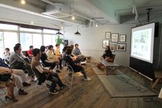 a group of people are sitting in chairs and watching a presentation on the projector screen