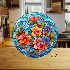 a stained glass plate with flowers on it sitting on a table in front of a window