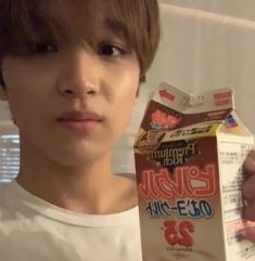 a young man holding up a carton of milk