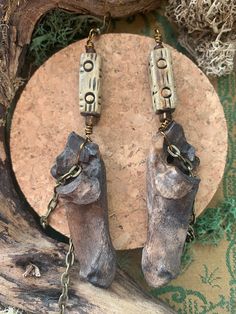 A pair of primitive, witchy, earthy bone earrings. The calcaneous / calcaneum bone is the heel bone, and this matching pair belong to the same roe deer. These earrings are surprisingly lightweight and come with two rectangular wooden beads with tribal markings, sandwiched between smaller dark beads. Chain details hang in front and behind the bones. The bones themselves are ethically-sourced and have been dyed black/brown with natural ingredients. They come attached to antique bronze earring hook Natural Wood Nature-inspired Jewelry, Bohemian Bone-colored Pierced Earrings, Bohemian Bone-colored Earrings, Real Bone Jewelry, Fairy Goth, Earthy Jewelry, Bone Earrings, Real Bones, Roe Deer