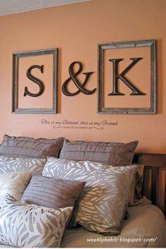 a bed with two framed pictures above it and the word s & k on the wall