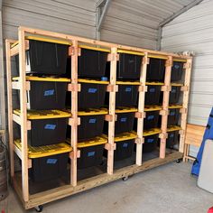 the shelves are filled with black boxes and plastic bins on wooden pallets in a storage room