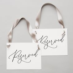 two white signs with silver ribbons hanging from the sides, one saying reserved and the other saying reserved