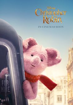 a pink teddy bear hanging from the side of a car window in front of a cityscape