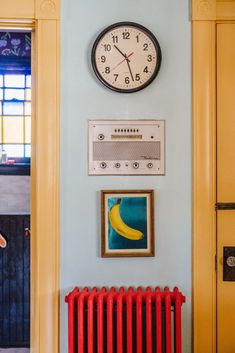 a wall with a clock, radiator and pictures on the wall next to it