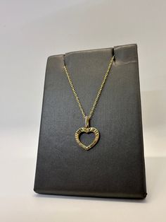 This open heart charm is made of 925 sterling silver with a 14K gold plating. It features simulated diamonds on the bail for some added sparkle. It comes paired with an 18" adjustable 14K gold plated silver cable chain. The heart features a diamond-cut design which allows the light to bounce off the pendant and shine beautifully.  * Stamped 925  * 14K Gold Plated * Diamond-Cut Design   * Adjustable chain 16" to 18"  * High Quality CZ Stones  * Heart measures 13mm w/o bail or jump   ring. * Heart Yellow Gold Open Heart Cubic Zirconia Jewelry, Open Heart Diamond Accents Necklace Gift, Diamond Accented Open Heart Necklace Gift, Open Heart Necklace With Diamond Accents As A Gift, Yellow Gold Open Heart Necklace, Cubic Zirconia Open Heart Charm Jewelry, Cubic Zirconia Open Heart Necklace In Fine Jewelry Style, Diamond Open Heart Necklace In Yellow Gold, Yellow Gold Diamond Open Heart Necklace