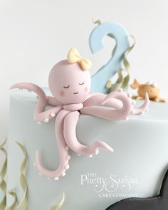 an octopus cake topper on a white frosted cake