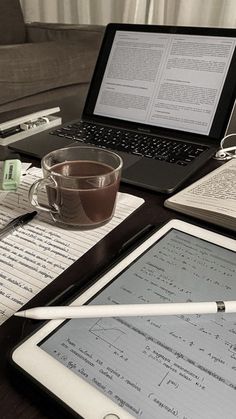 a laptop computer sitting on top of a wooden desk next to a cup of coffee