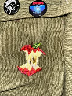 the back pocket of a jacket with patches on it and an apple in the pocket