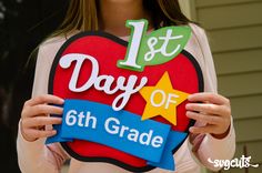 a girl holding up a sign that says 1st day of 6th grade with an apple