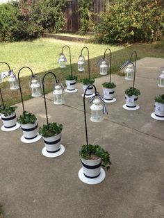 several white and black planters with plants in them on the ground near some grass