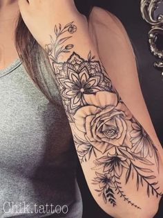 a woman's arm with flowers and leaves tattooed on the side of her arm