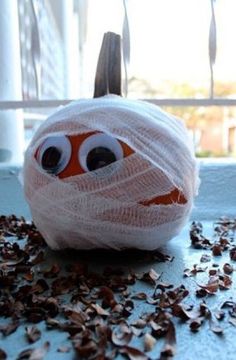 an orange and white ball wrapped in plastic wrap with eyes on it sitting on a table