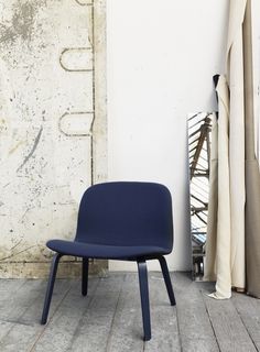 a blue chair sitting on top of a wooden floor next to a white wall and window