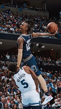 a basketball player jumping up to dunk the ball in front of an audience at a sporting event