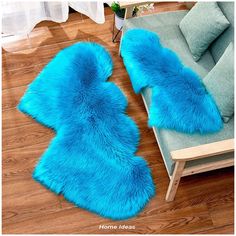 two blue fur rugs sitting on top of a wooden floor next to a couch