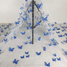 there is a tree with blue butterflies on it and white netting covering the branches,