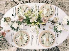 an overhead view of a table set with place settings and flowers on the plateware