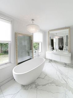 a large white bathtub sitting next to a window in a bathroom with marble flooring