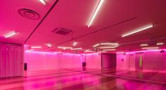 an empty room with pink lighting in the ceiling and hard wood flooring on both sides