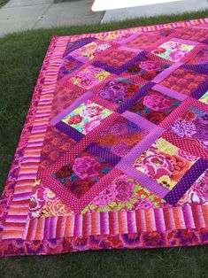 a patchwork quilt is laying on the grass