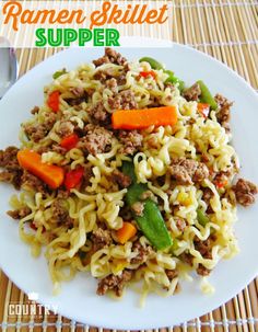 a white plate topped with noodles and meat next to a fork on top of a table