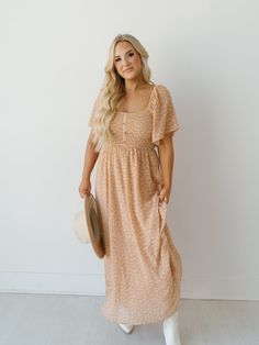 Meet the new "Rachel Dress!" A stunning maxi dress is such a chic and feminine option to wear as an everyday elevated piece or as a date night ensemble! Adorned with a small floral print on a blush colored base, along with short flutter sleeves on elastic bands. The smocked bust and back add a comfortable and flattering silhouette before the flowy skirt! Detailed Fit: Orange floral maxi dress Square neckline Cinching through front and back bodice Button detail (they do not button and unbutton) A Bohemian Floor-length Dress With Smocked Bodice, Spring Maxi Dress With Smocked Bodice, Knee-length, Bohemian V-neck Maxi Dress With Smocked Back, Spring Bohemian Smocked V-neck Dress, Summer Smocked Dress With Ditsy Floral Print, Mini Length, Flowy Skirt, Blush Color, Elastic Band, Flutter Sleeve