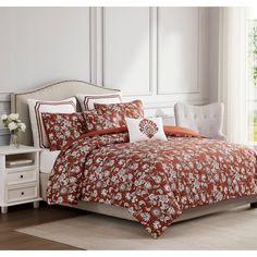 a bed with an orange and white comforter on it