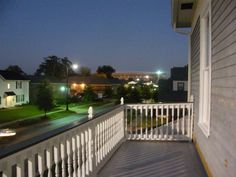 a balcony with white railings and lights on the buildings in the background at night