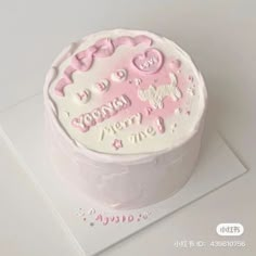 a white cake with pink frosting on top of a card and some other decorations