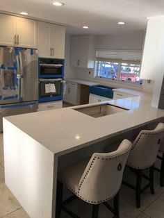 a kitchen with an island and two chairs in front of the counter top that has been painted white