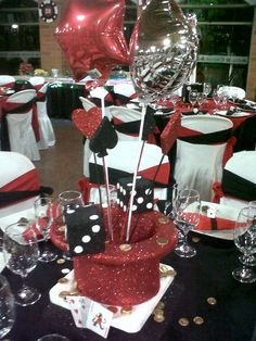 a table with black and white tables cloths, silverware, red heart shaped balloons