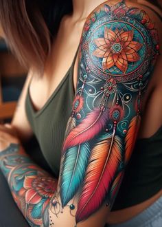 a woman's arm with colorful tattoos and feathers on her arm, which has a flower in the center