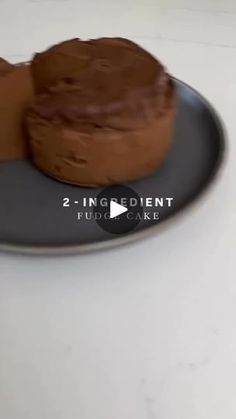 two pieces of chocolate cake sitting on top of a black and gray plate with the words 2 ingredient fudge cake